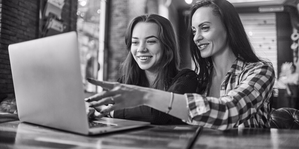 Person smiling while using a laptop at a desk.
