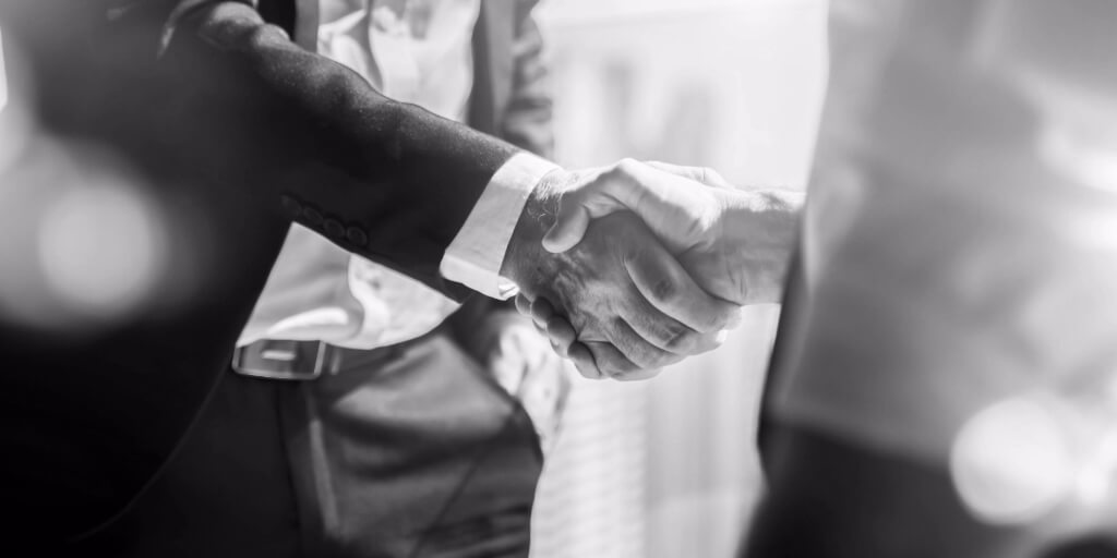 Close-up image of man in business suit shaking hands with another man.