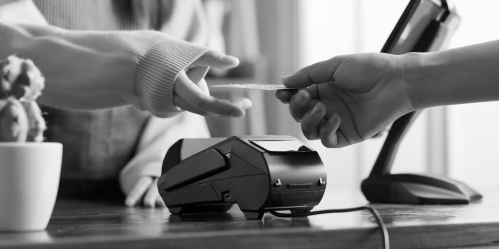 A woman in a sweater takes a credit card from a customer.