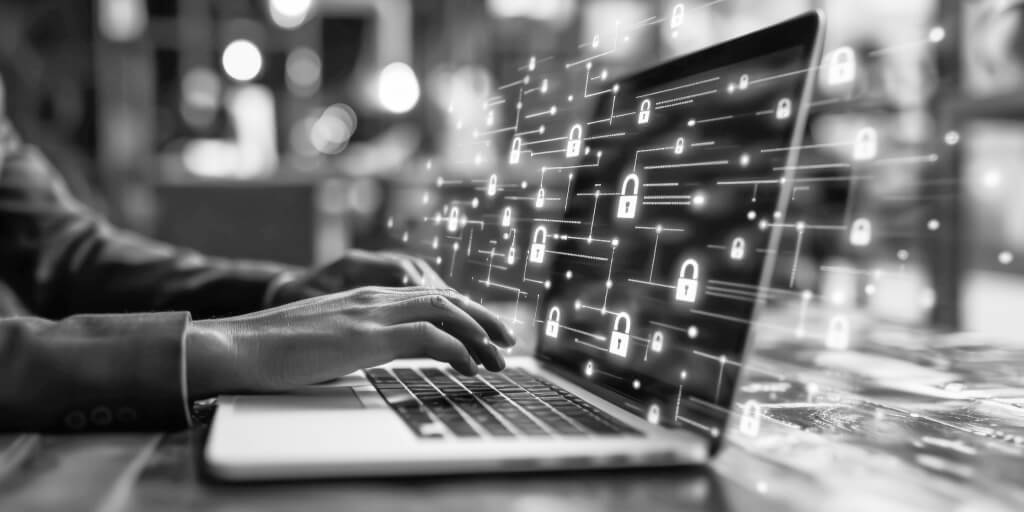 The hands of a person using a laptop with virtual padlock icons displayed on the screen, symbolizing cyber and data security. 